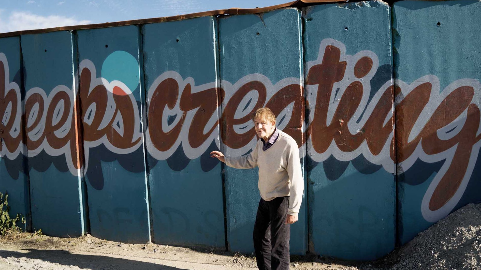 Per Nørgård in front of a mural reading 'keeps creating'